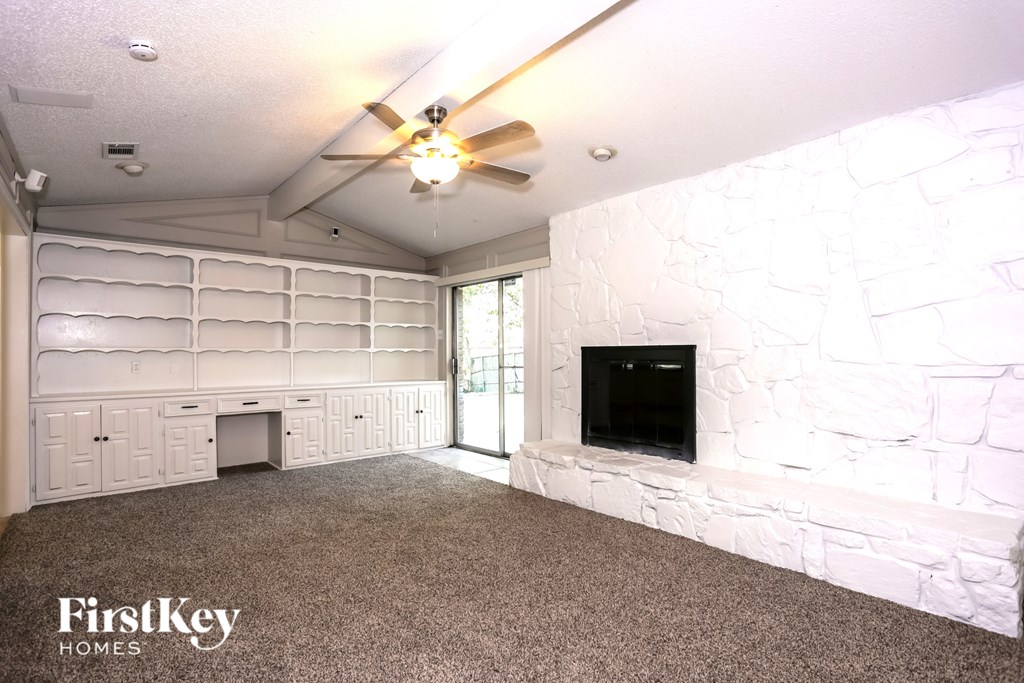 A room with a ceiling fan and a flat screen TV mounted on a stone wall.