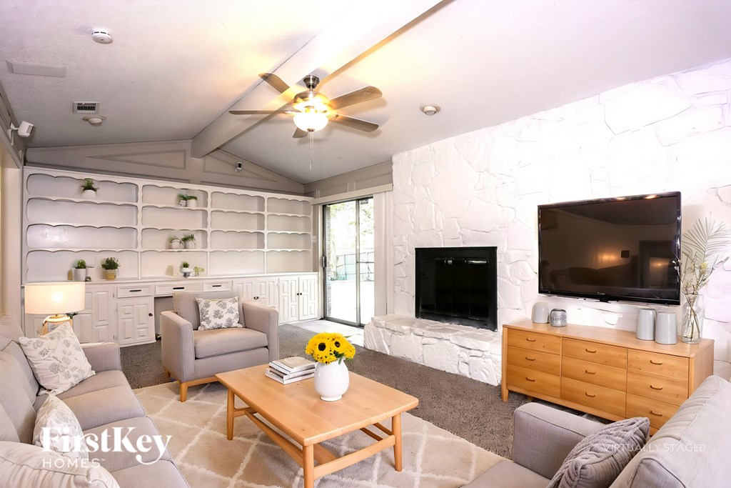 A living room with a grey couch, a wooden coffee table, and a flat screen TV mounted on the wall.