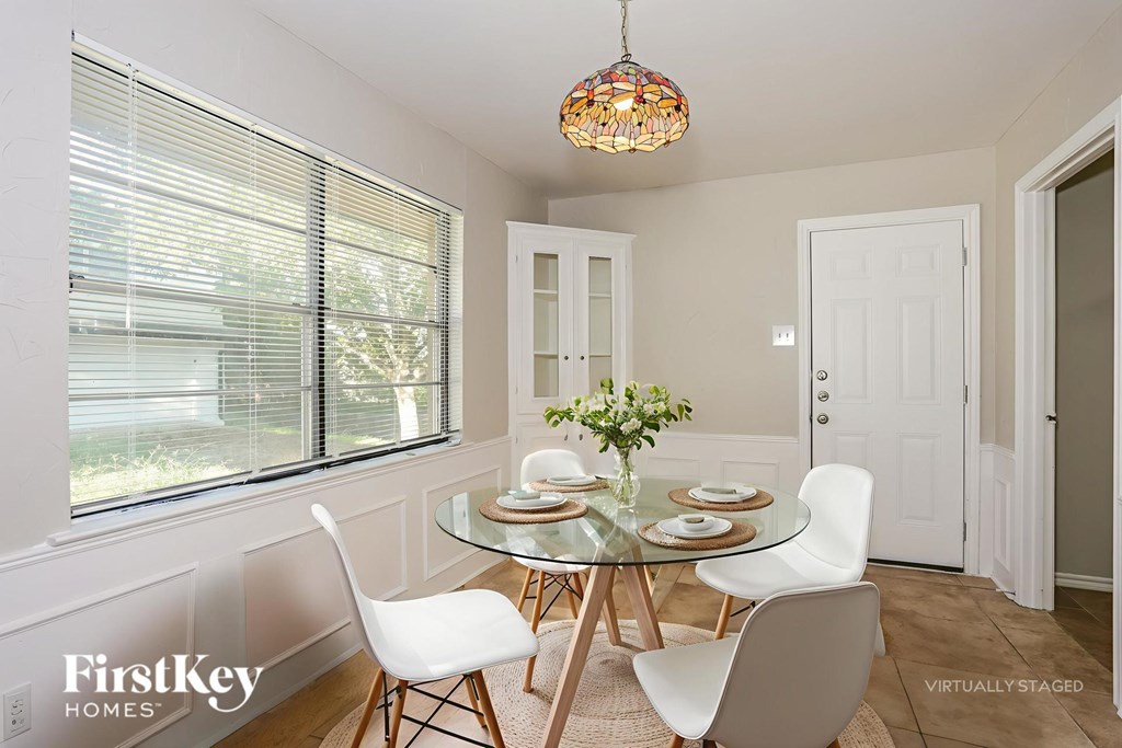 A dining room with a glass table and white chairs.