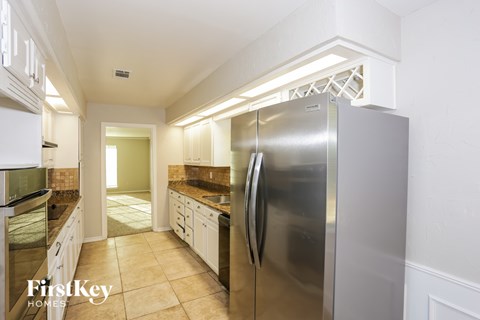 A kitchen with a stainless steel refrigerator and white cabinets.