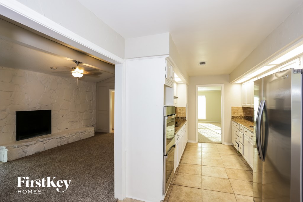 A kitchen with a stainless steel refrigerator and a stone fireplace.
