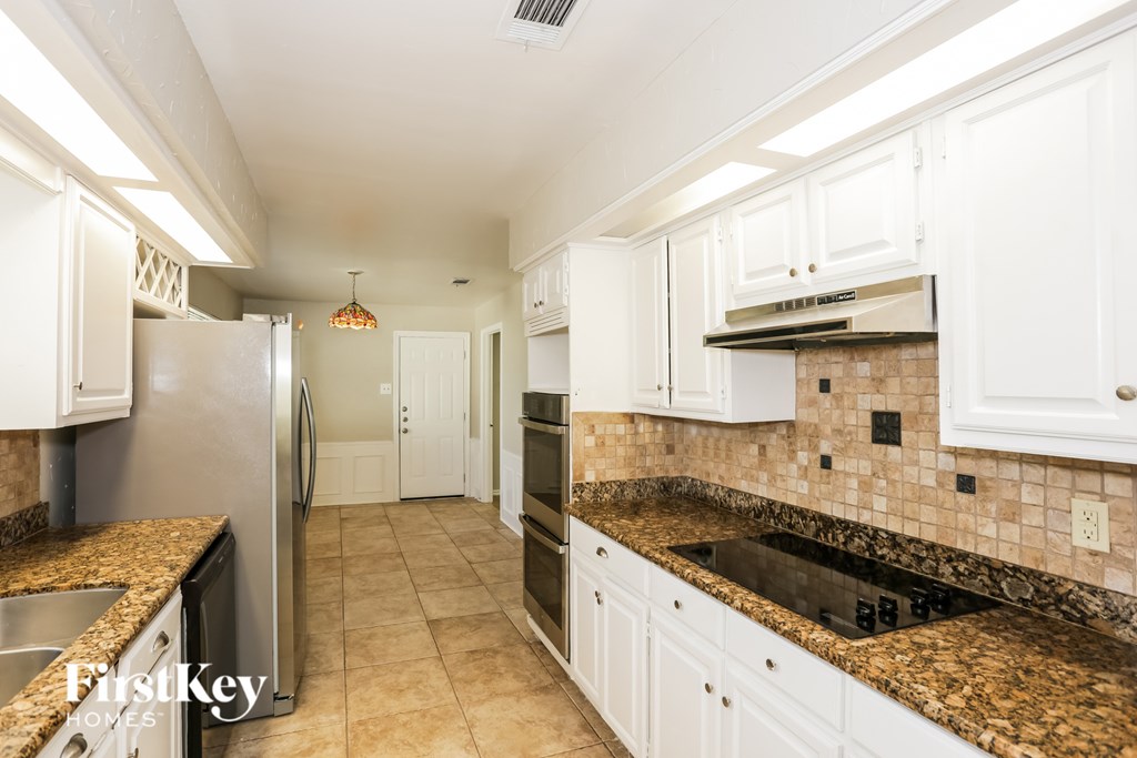 A kitchen with white cabinets and a granite counter top.