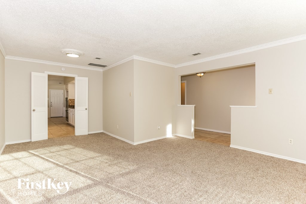 A spacious room with a carpeted floor and two open doors.