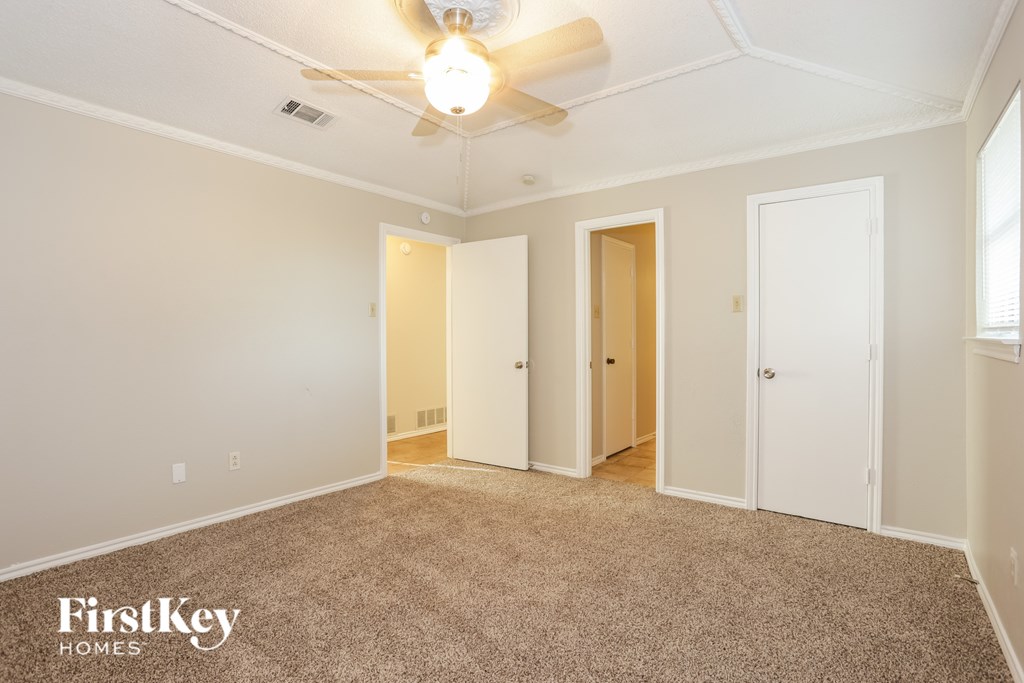 A spacious room with a carpeted floor and a ceiling fan.