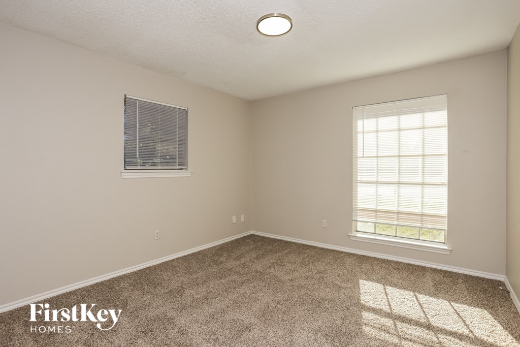 A room with a window and a carpeted floor.