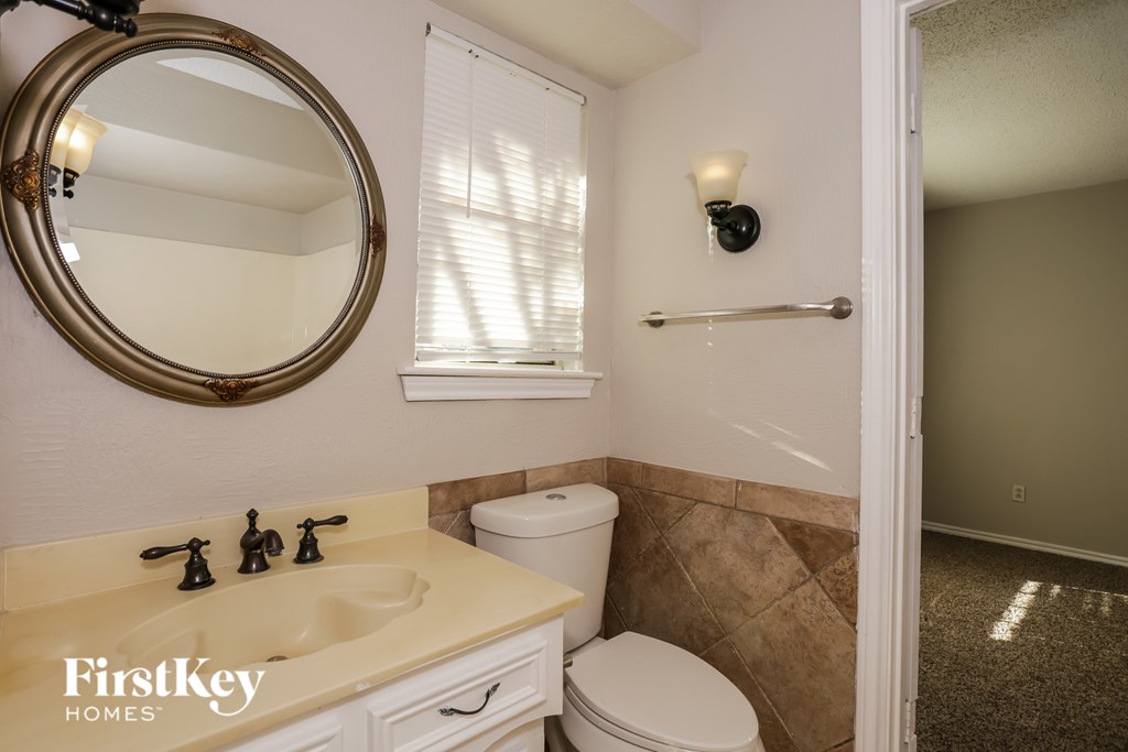 A bathroom with a toilet, sink, and mirror.