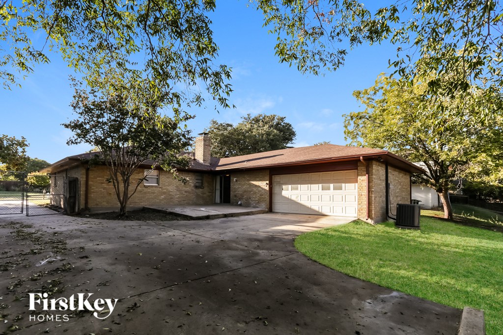 A house with a driveway and a tree in front of it.