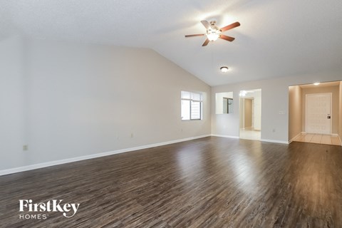 A spacious room with wooden flooring and a ceiling fan.