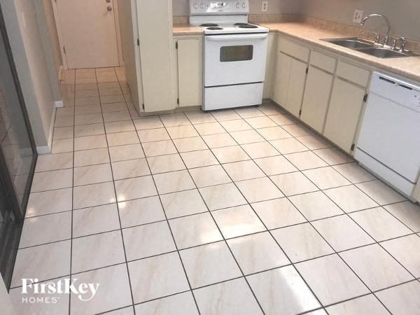 A kitchen with white appliances and white tiled floors.
