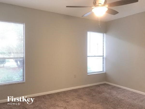 A room with a carpet floor, a ceiling fan, and a window with blinds.