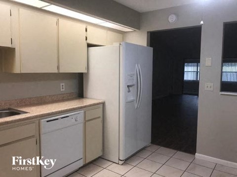 A kitchen with a white refrigerator and a dishwasher.