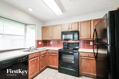 A kitchen with wooden cabinets and black appliances.