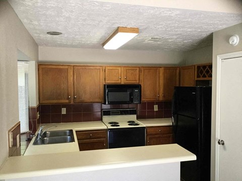 A kitchen with black appliances and wooden cabinets.
