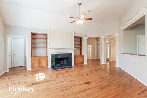 a living room with a fireplace and wooden floors and a ceiling fan