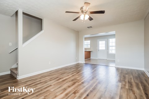 A spacious room with wooden floors and a ceiling fan.