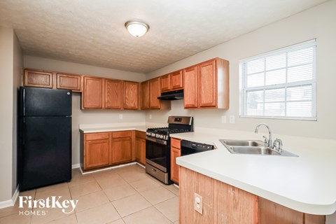 A kitchen with wooden cabinets and a black fridge.