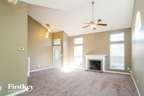 A spacious living room with a fireplace and a ceiling fan.
