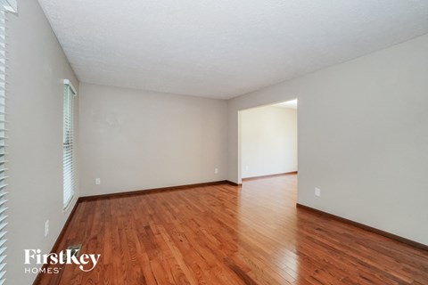 a spacious living room with hardwood flooring and white walls