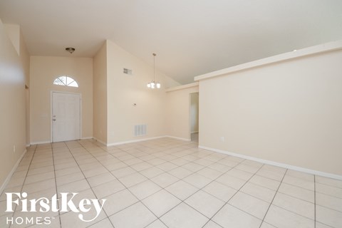 a spacious living room with white tile flooring and a white door