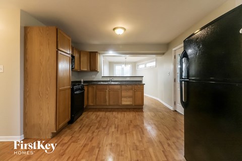 A kitchen with wooden cabinets and a black refrigerator.