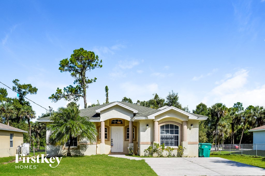 a house with a driveway and palm trees in front of it