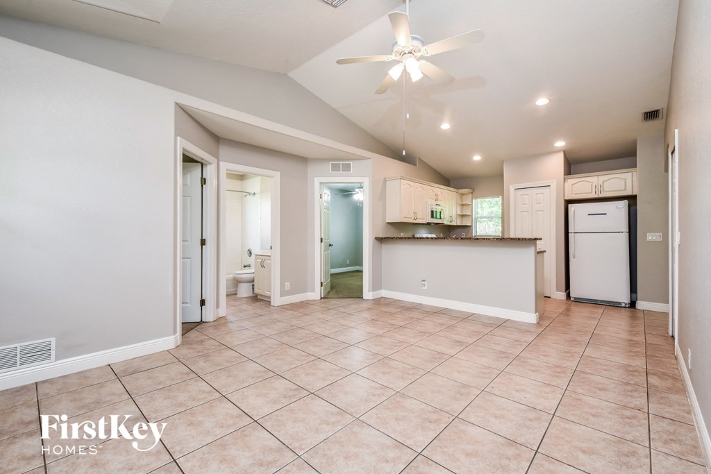 an open kitchen and living room with tile flooring and a ceiling fan