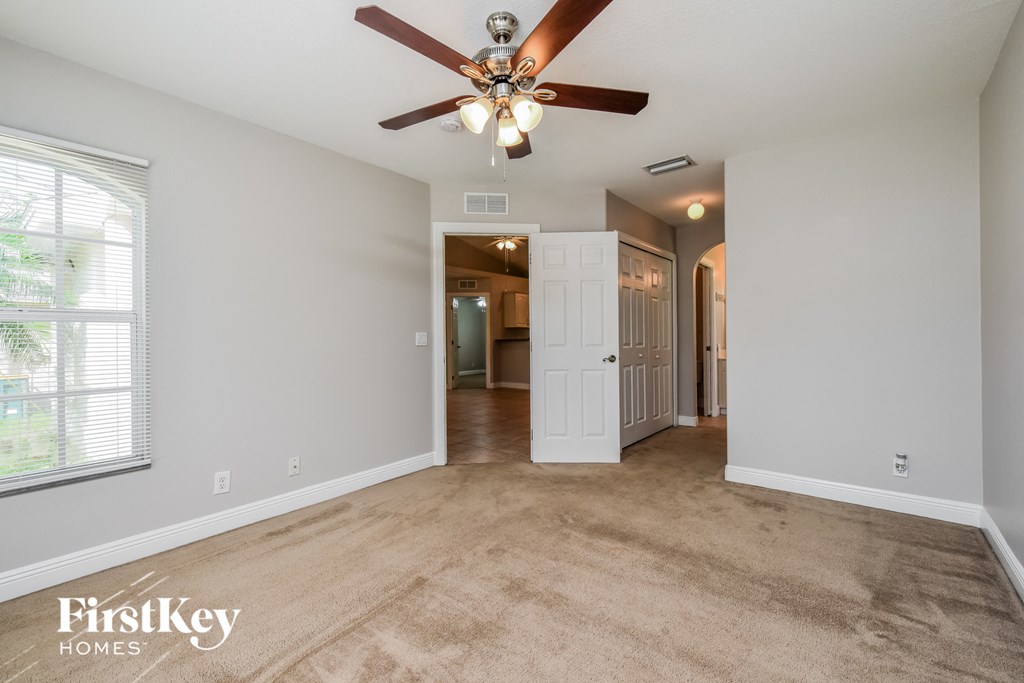 an empty living room with a ceiling fan and a door to a hallway
