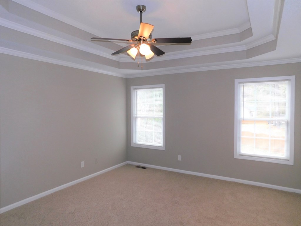 an empty room with a ceiling fan and two windows