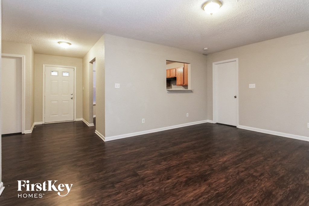 an empty living room with wood flooring and white walls