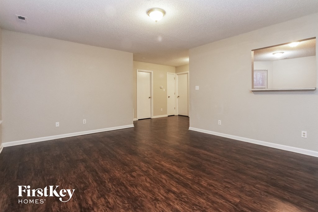 an empty living room with wood flooring and white walls