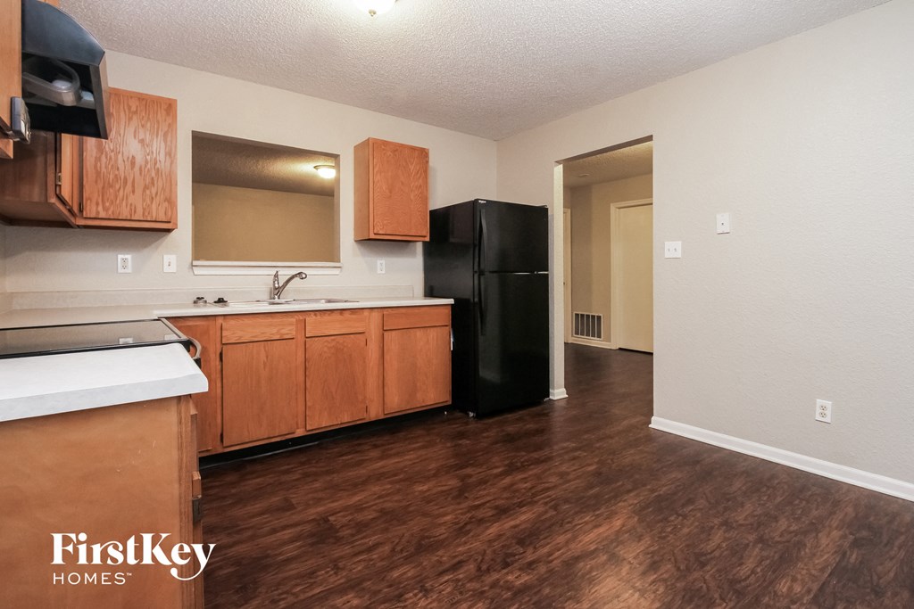 a kitchen with wooden cabinets and a black refrigerator