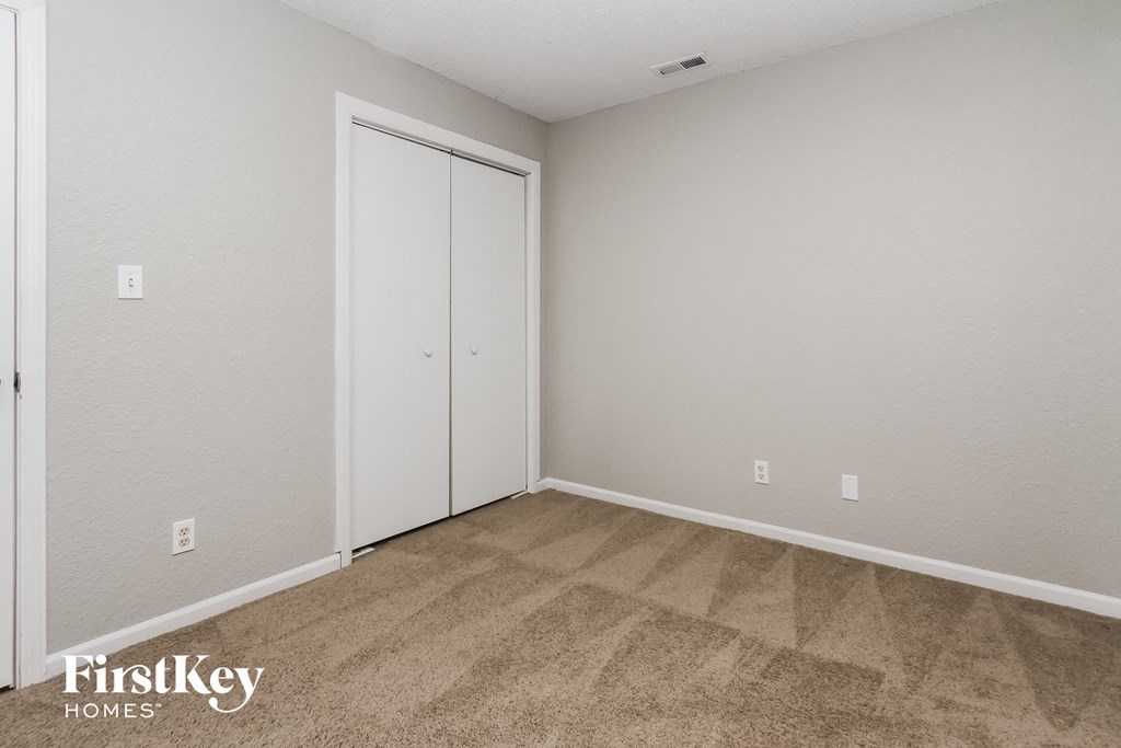 a bedroom with carpet and a door to a closet