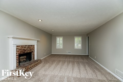 A spacious room with a fireplace and carpeted floor.