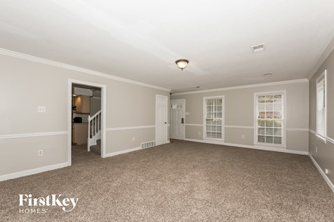 a spacious living room with carpet and a door to the kitchen