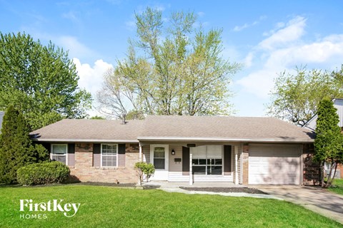 a white brick house with a lawn and trees