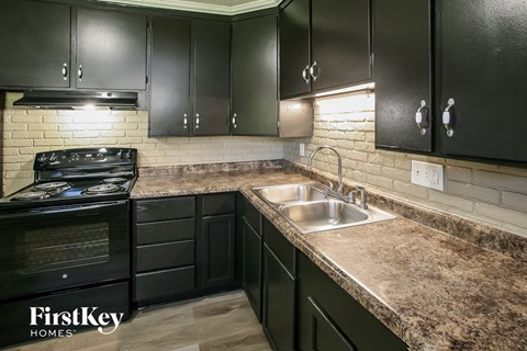 a kitchen with black cabinets and granite counter tops and a sink