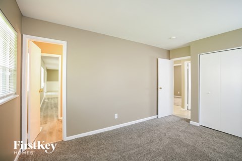 a bedroom with a carpeted floor and a door to a hallway