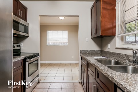 A kitchen with a stainless steel refrigerator and a granite countertop.