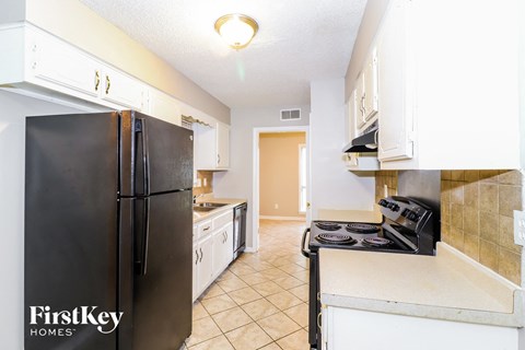 A kitchen with a black refrigerator and a black stove top oven.