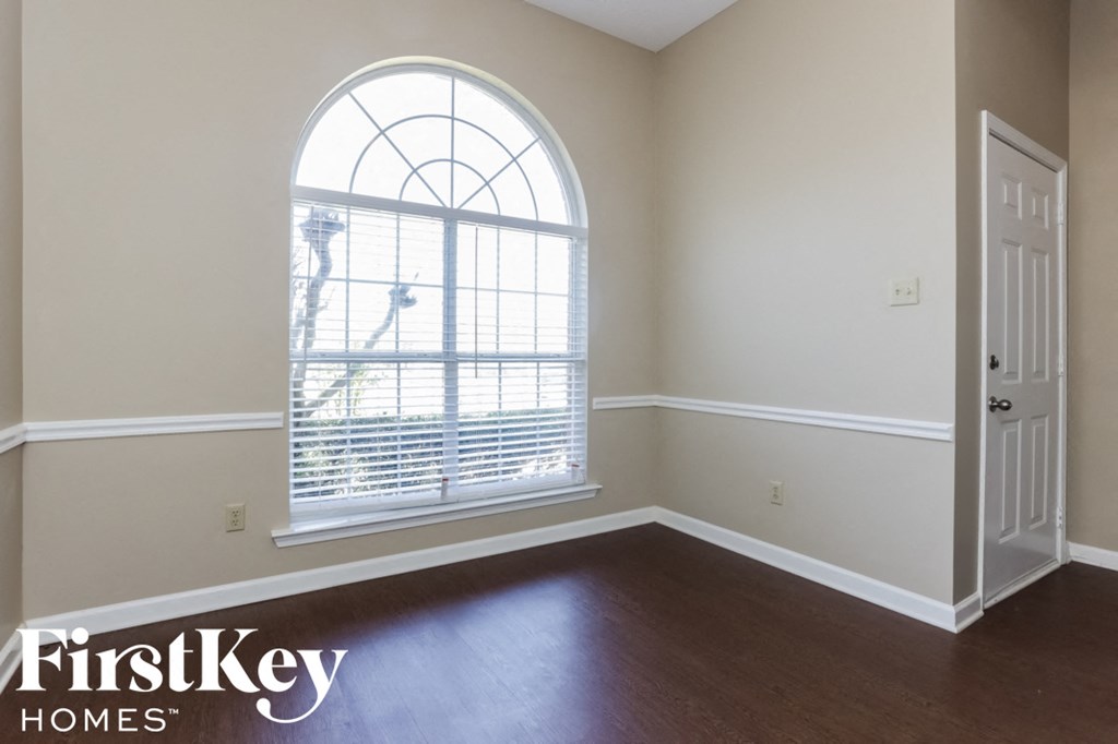 A room with a large arched window and wooden flooring.