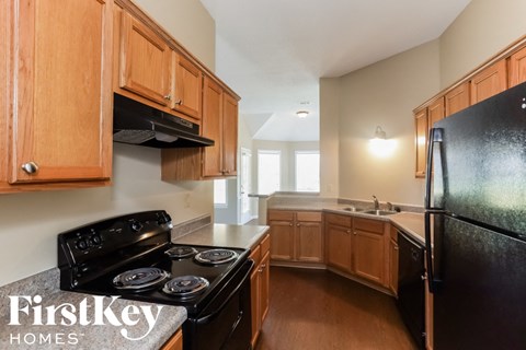 A kitchen with wooden cabinets and a black refrigerator.