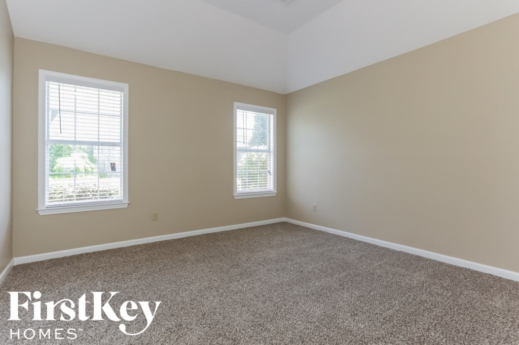 A room with two windows and a carpeted floor.