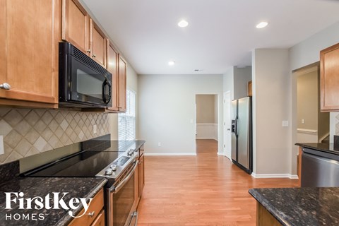 A kitchen with wooden cabinets and a black microwave.