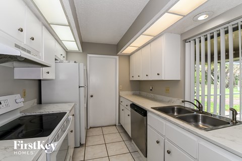 A kitchen with white cabinets and appliances.
