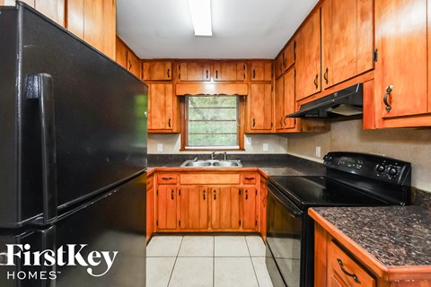 A kitchen with wooden cabinets and a black refrigerator.