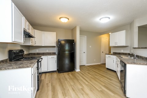 A kitchen with white cabinets and a black refrigerator.