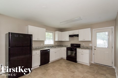 A kitchen with a black fridge and stove top oven.