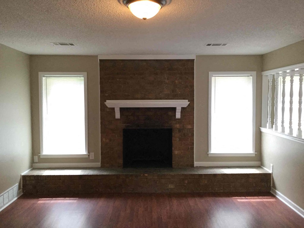 A room with a fireplace and two windows.