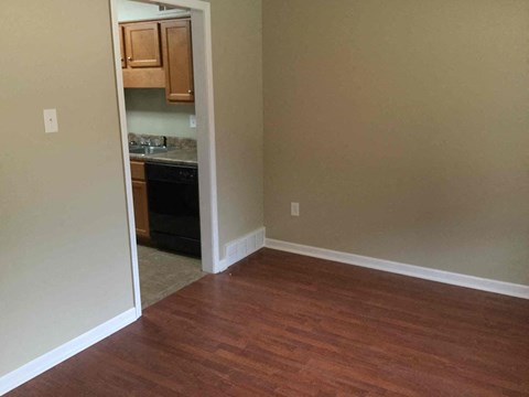 A kitchen with wooden floors and cabinets is visible from the living room.