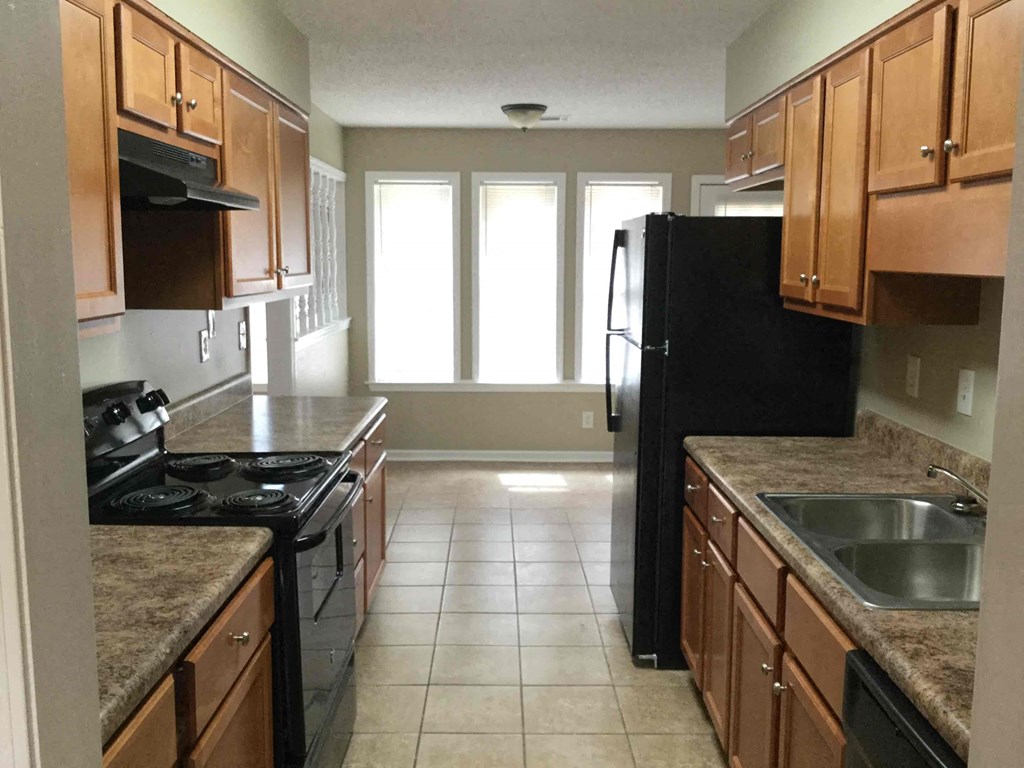 A kitchen with black appliances and wooden cabinets.